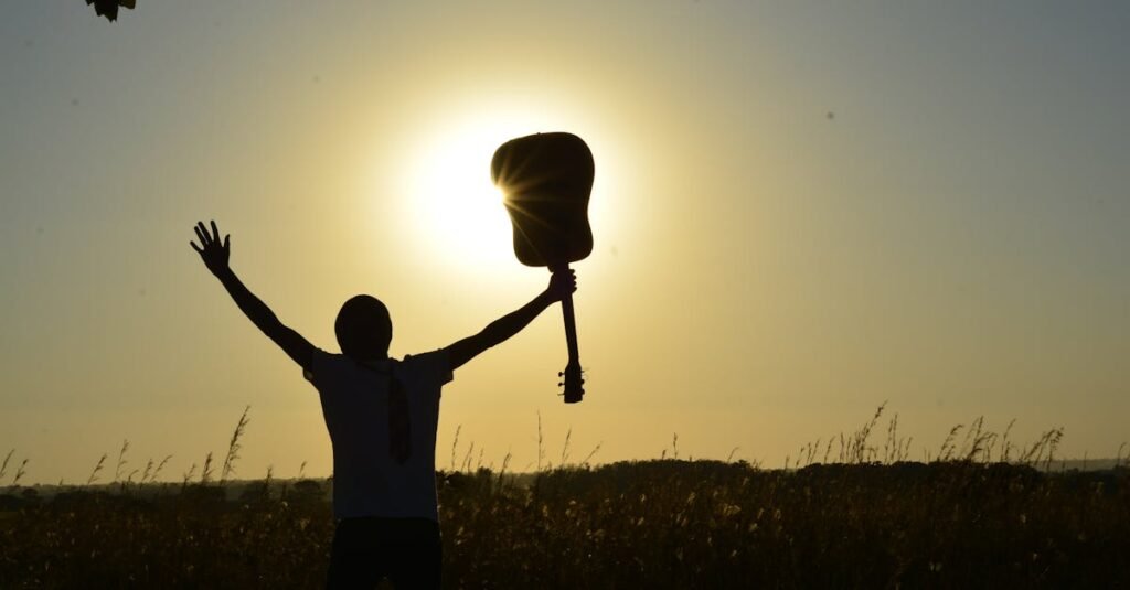 A young guitarist celebrates the sunrise with an acoustic guitar, creating a dramatic silhouette.
